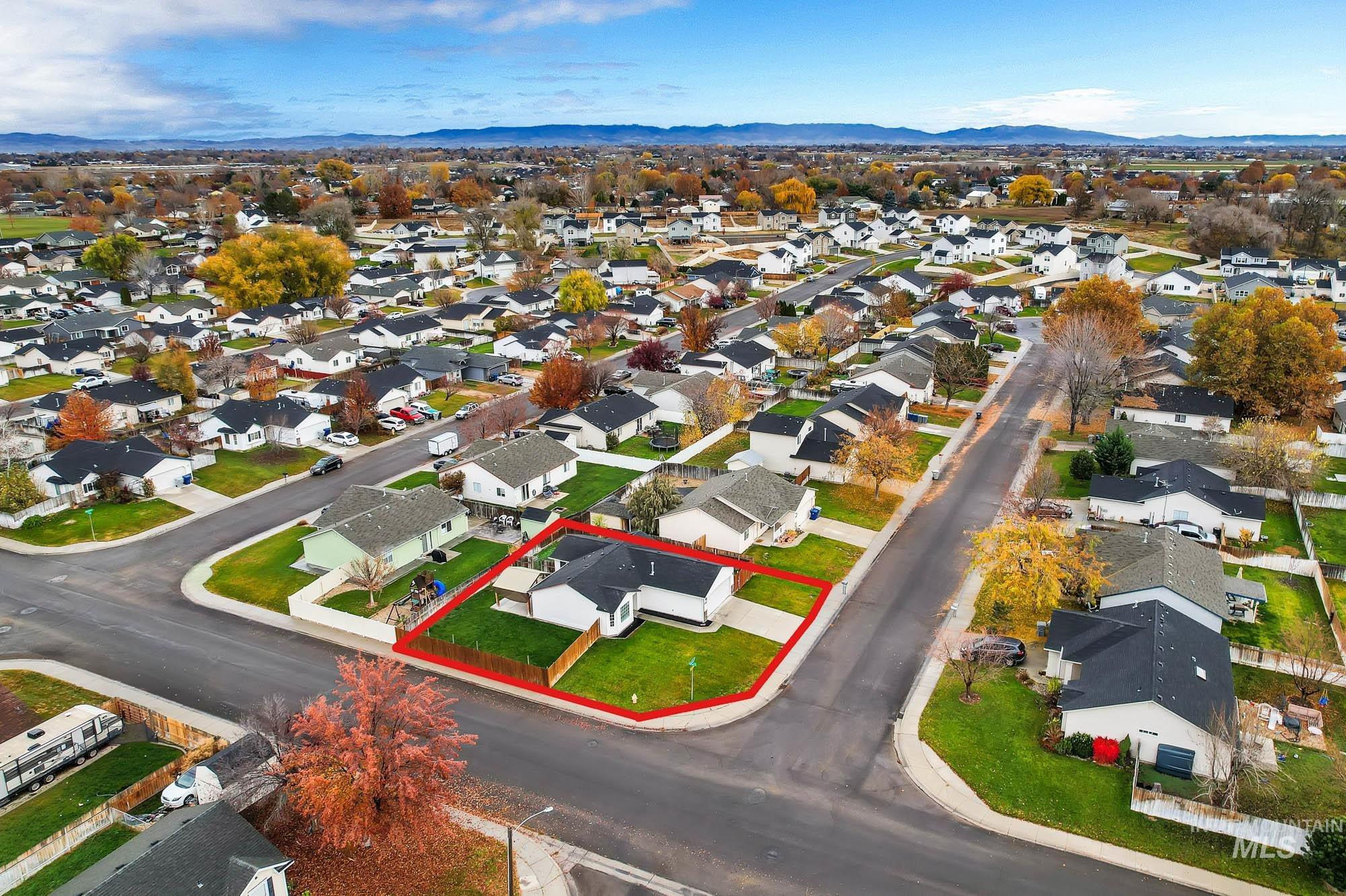 Aerial view of residential area featuring property boundaries highlighted and mountains