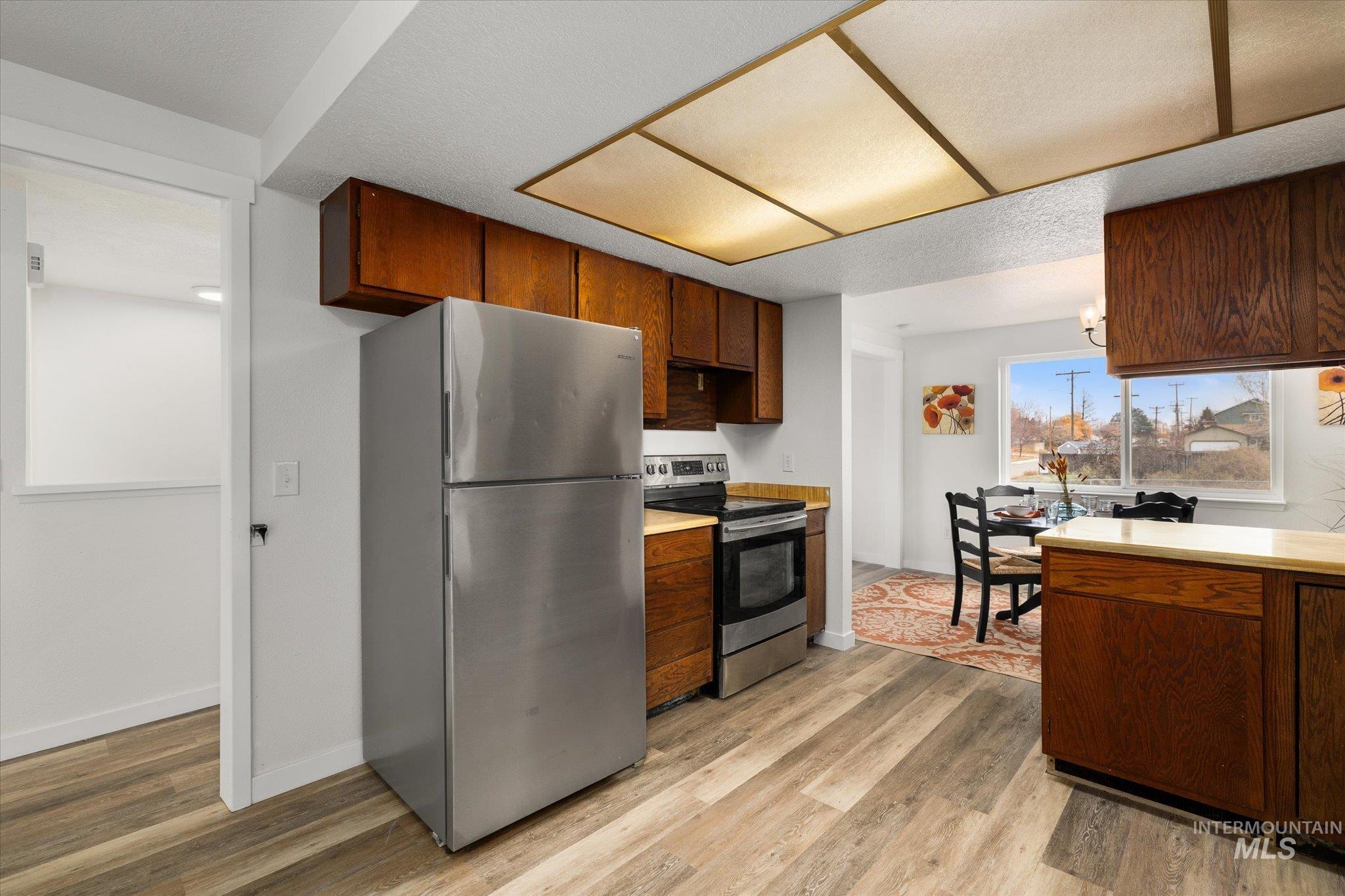 Kitchen featuring stainless steel appliances, light countertops, and light wood-style flooring