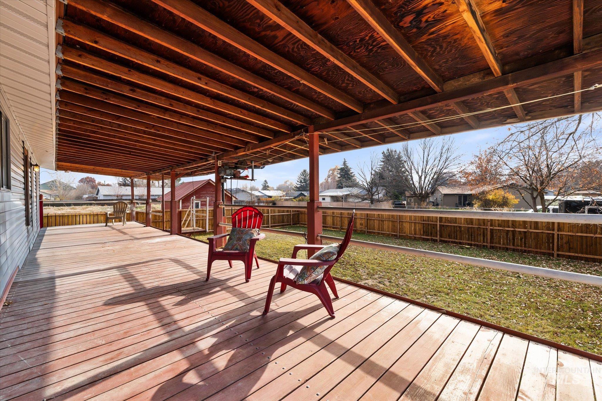 Wooden terrace with a fenced backyard and a storage unit