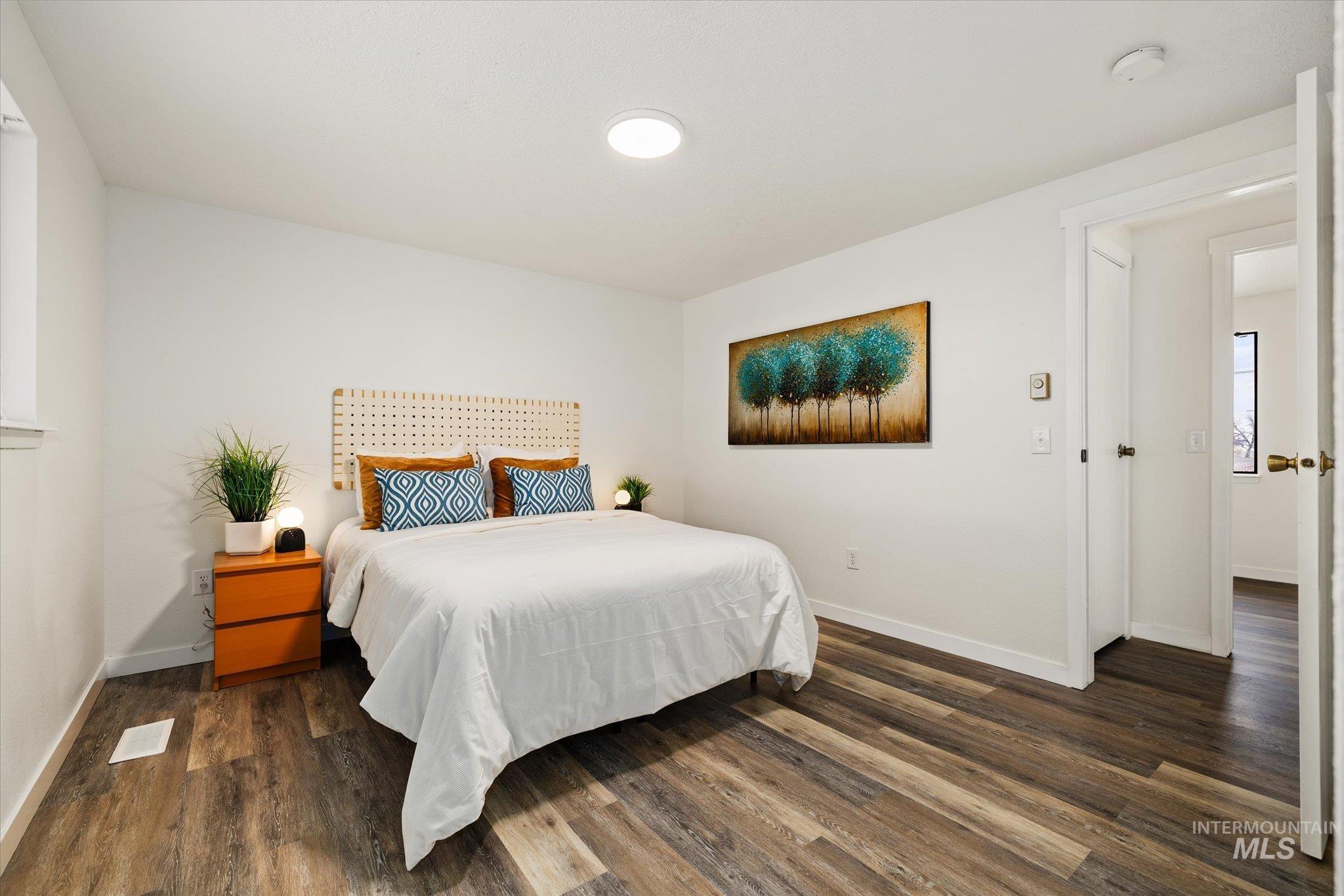Bedroom with dark wood-style flooring and baseboards