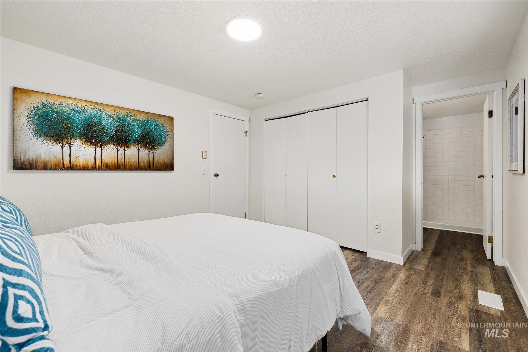 Bedroom with dark wood-style flooring and a closet