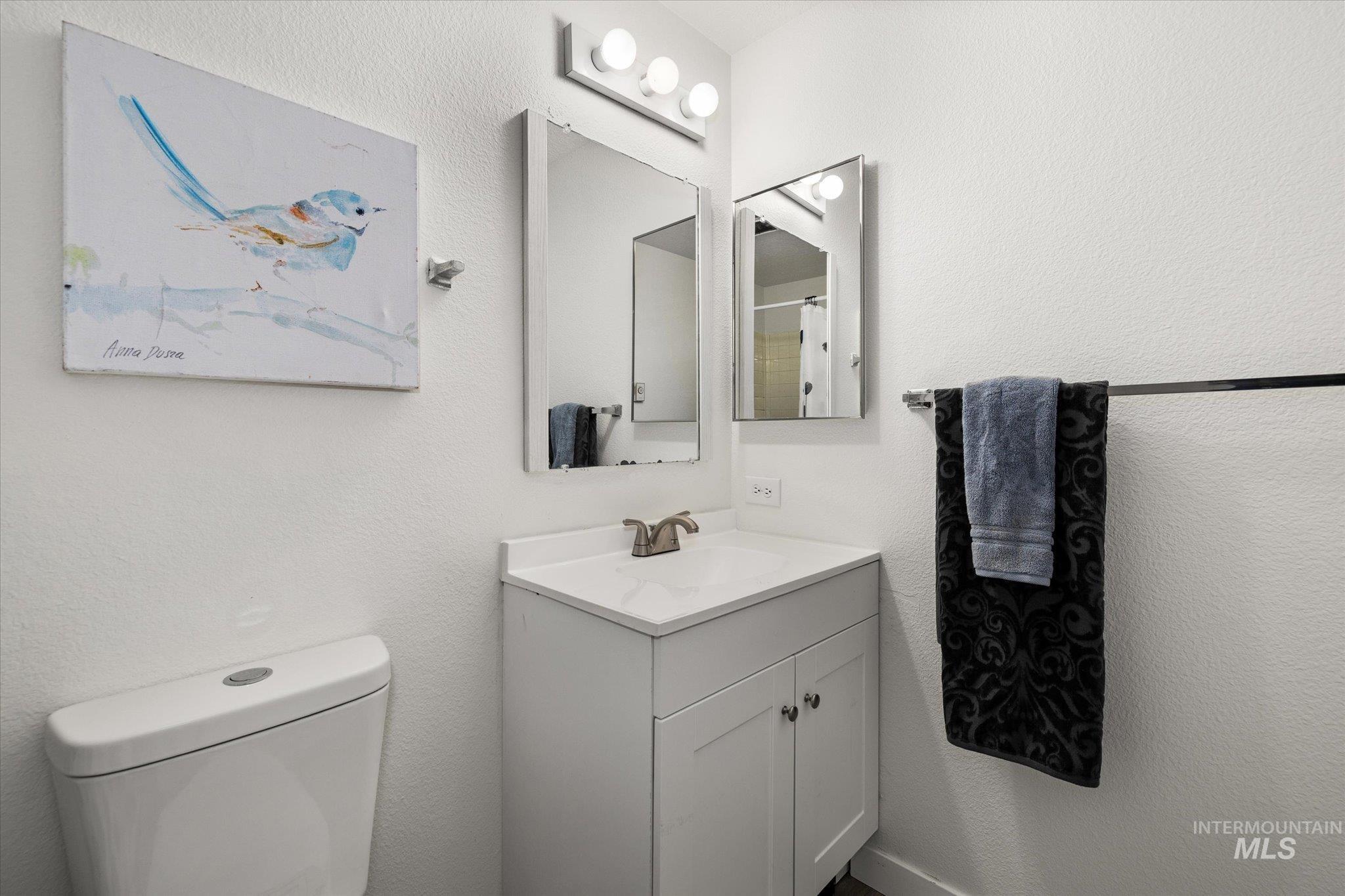 Full bath featuring a textured wall, vanity, and a shower with shower curtain