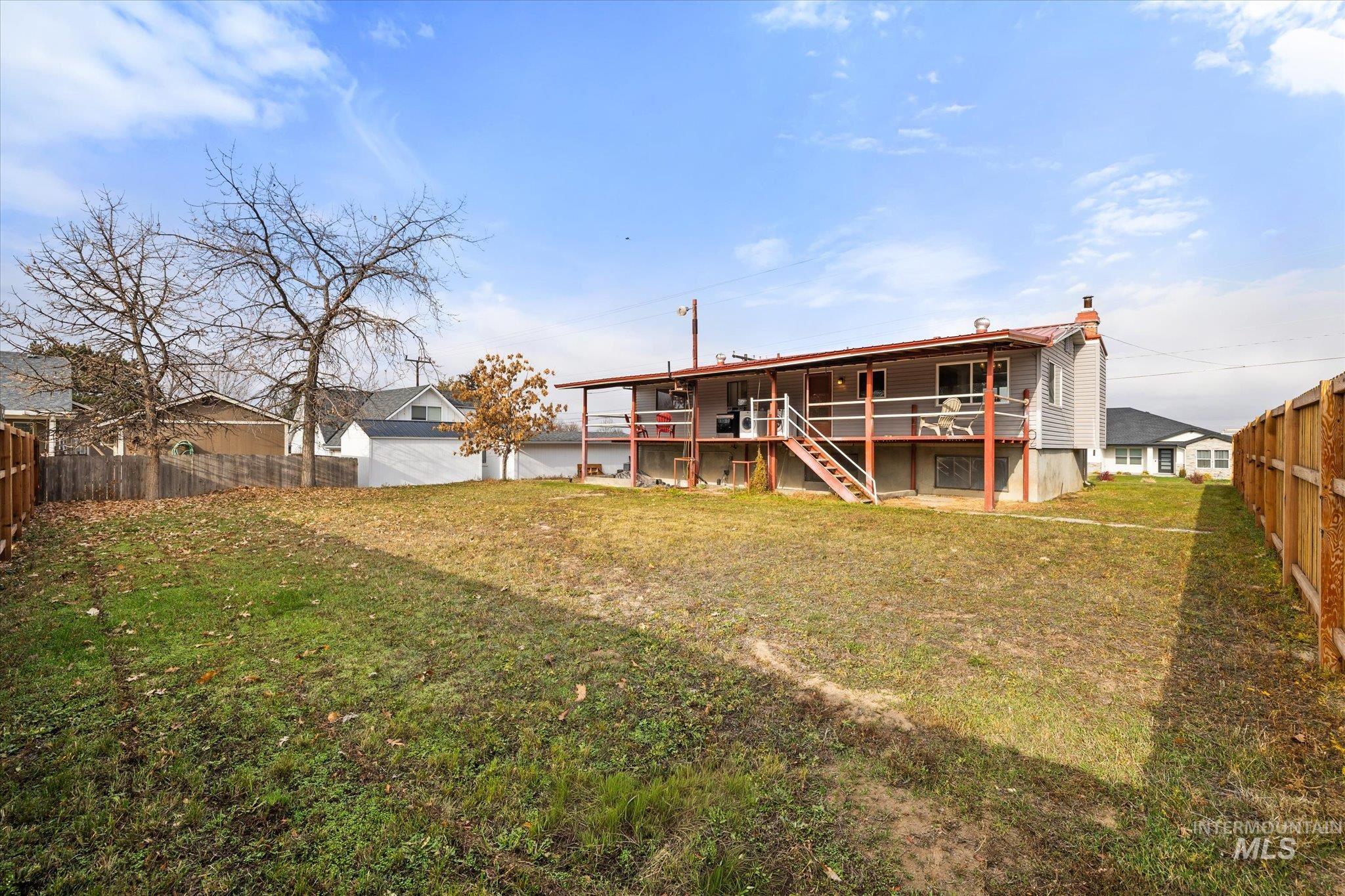 Rear view of house with a fenced backyard, a wooden deck, and stairway