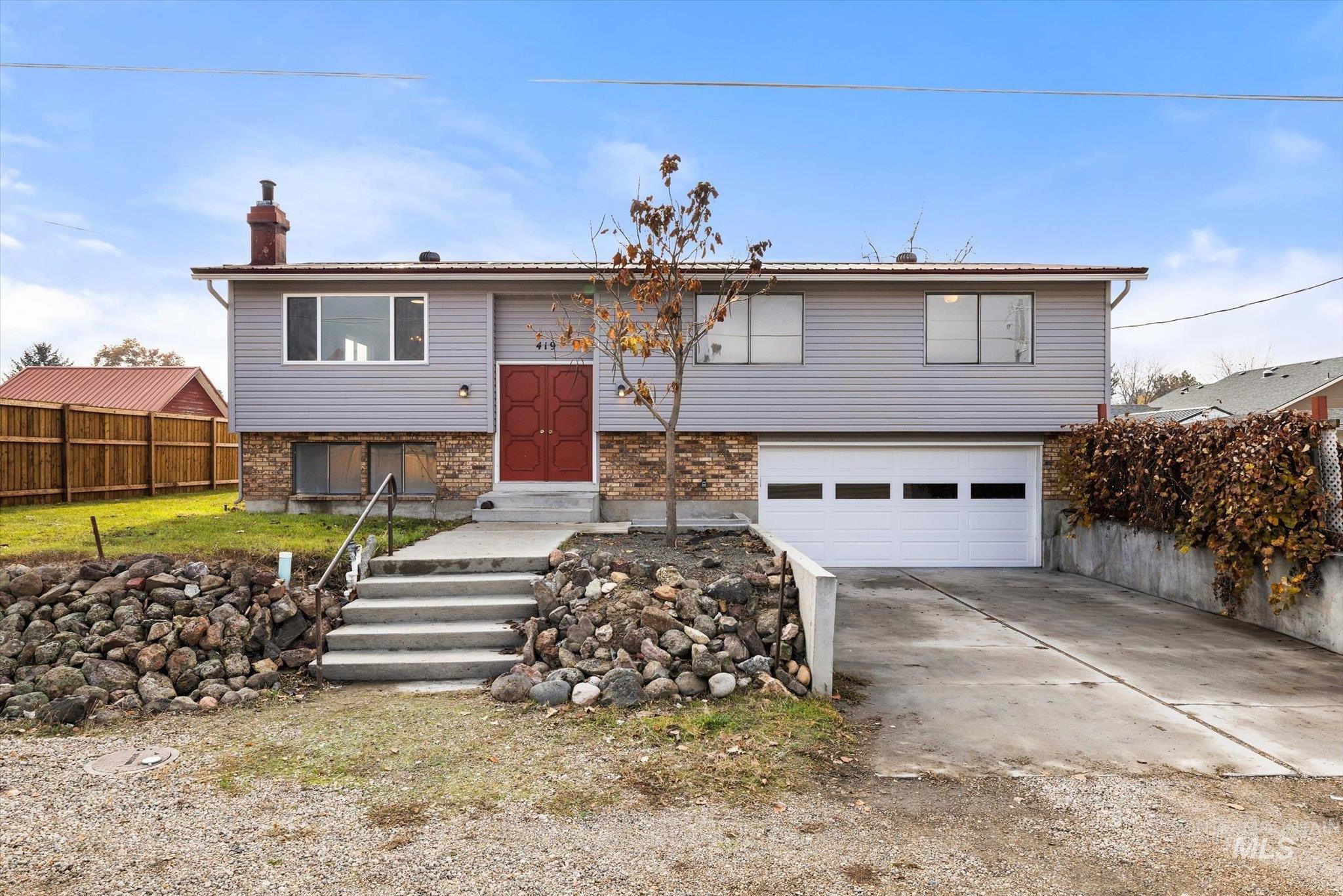 Bi-level home with brick siding, a chimney, concrete driveway, and an attached garage