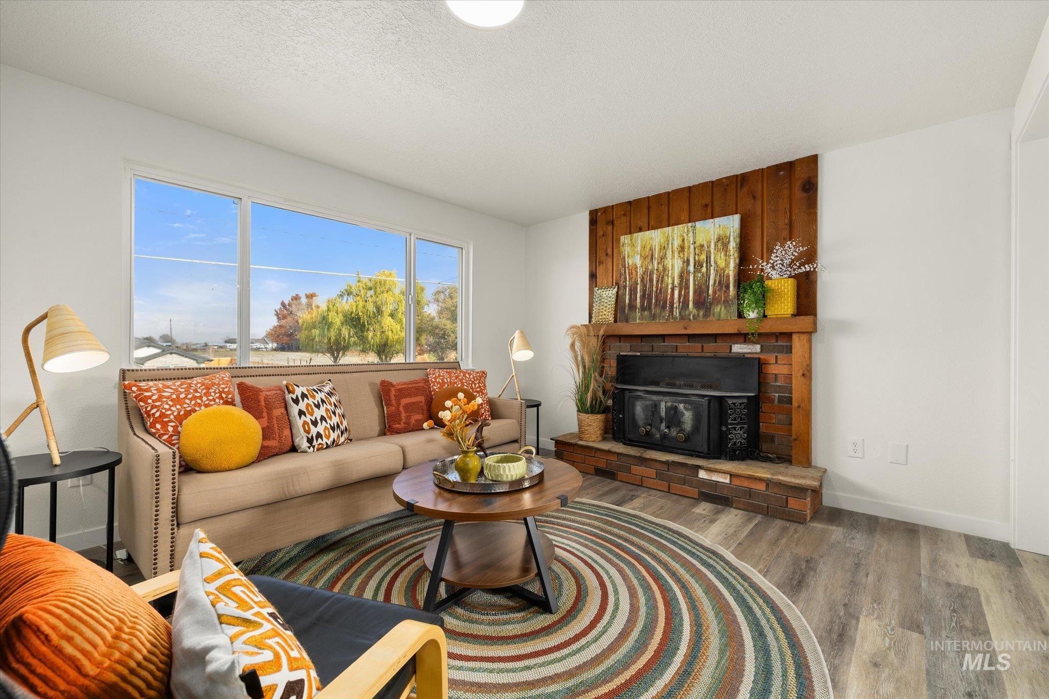 Living room with a fireplace, wood finished floors, and a textured ceiling