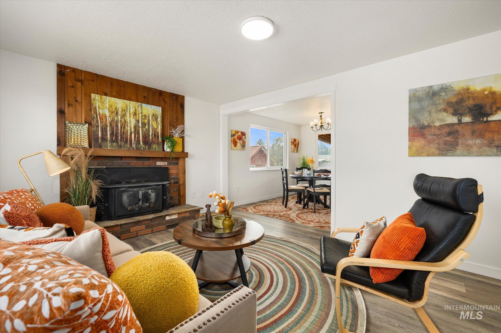 Living area with wood finished floors, a brick fireplace, and a chandelier