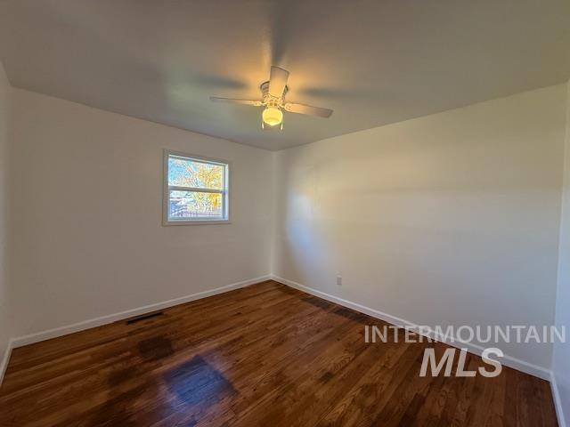 Empty room featuring dark wood-style floors and a ceiling fan