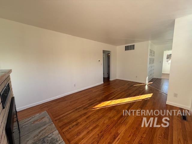 Unfurnished living room featuring dark wood-type flooring and baseboards