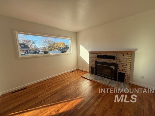 Unfurnished living room featuring a brick fireplace and light wood finished floors