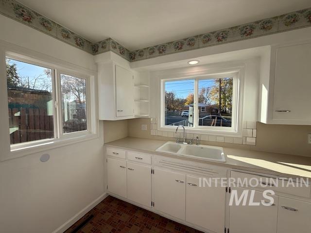 Kitchen with white cabinetry, light countertops, and open shelves