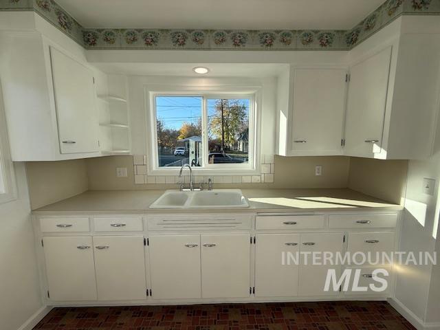 Kitchen featuring light countertops, open shelves, and plenty of natural light