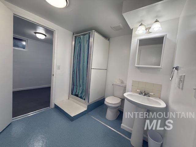 Full bath featuring a shower stall and toilet