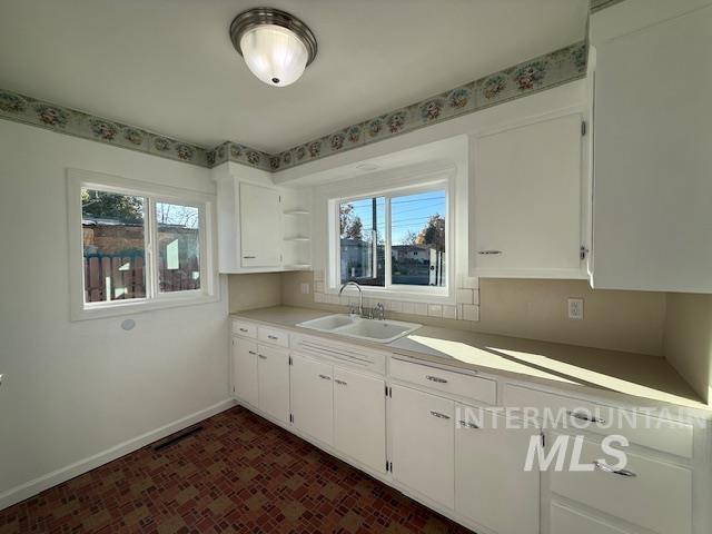 Kitchen with white cabinets, healthy amount of natural light, and light countertops
