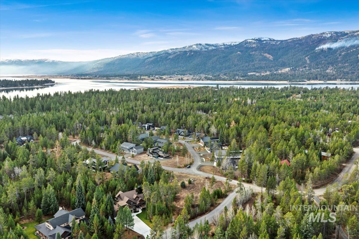 Aerial view of property and surrounding area with a mountain backdrop and a forest