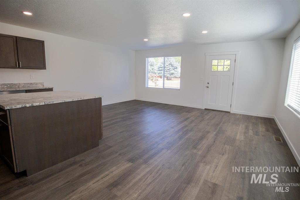 Kitchen with recessed lighting, healthy amount of natural light, dark brown cabinetry, a center island, and dark wood-type flooring