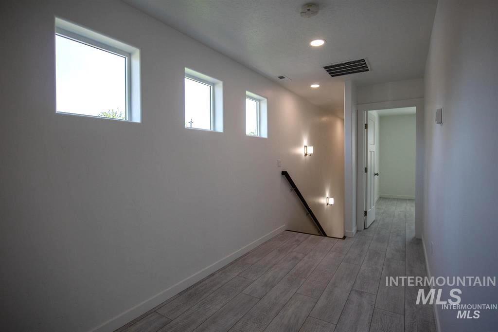 Corridor with an upstairs landing, recessed lighting, and light wood-type flooring