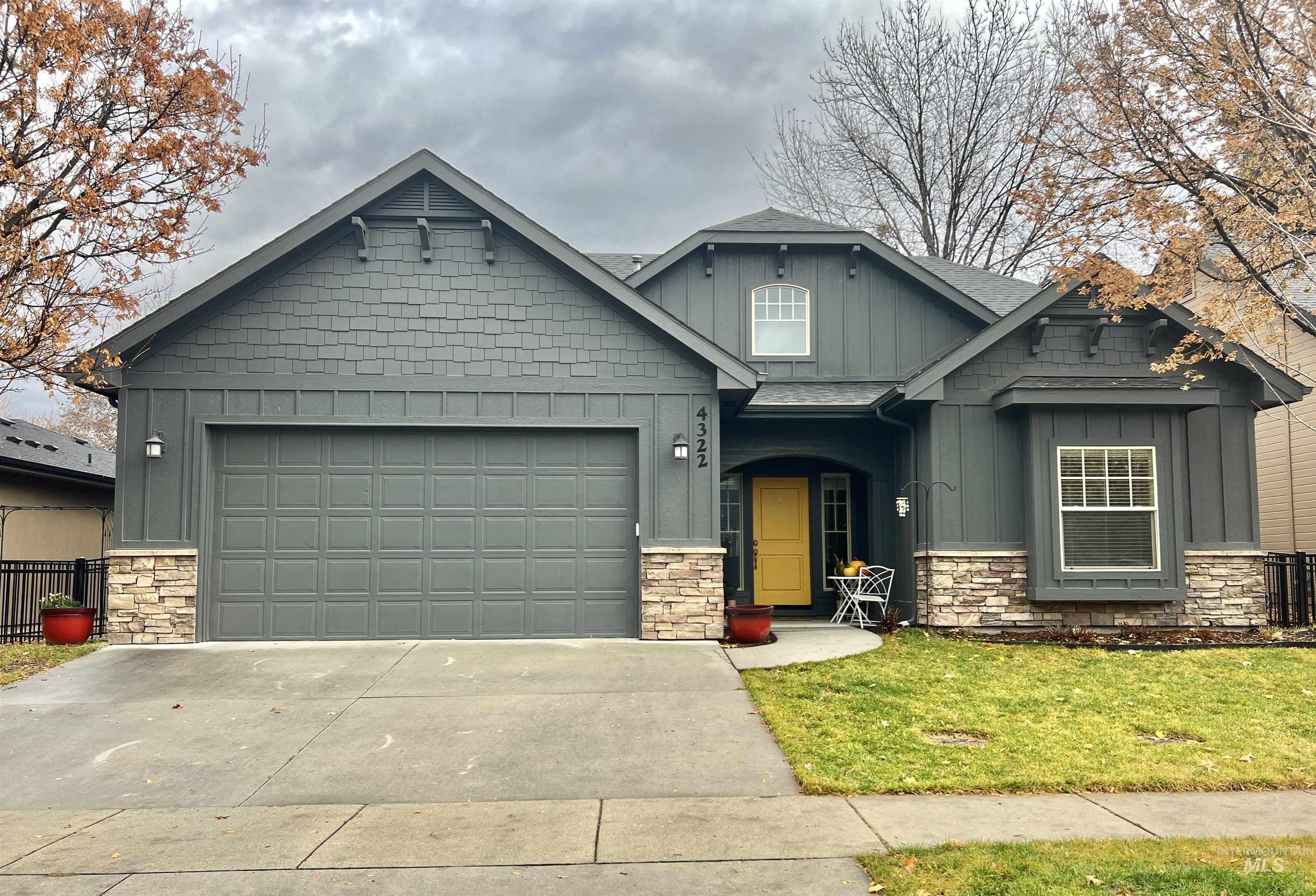 Craftsman house featuring board and batten siding, stone siding, driveway, a front lawn, and an attached garage