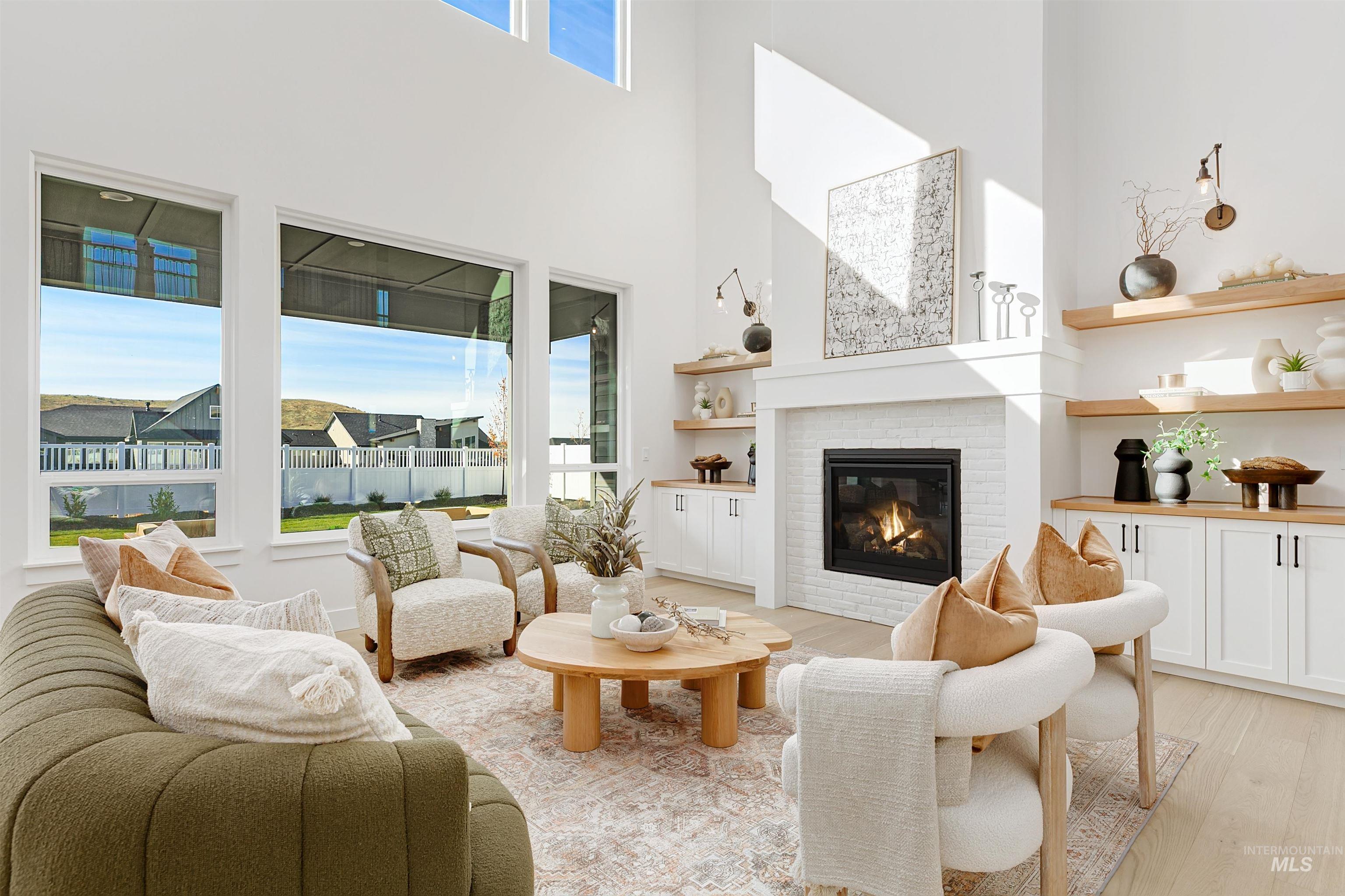 Living area featuring light wood-type flooring, a towering ceiling, and a fireplace