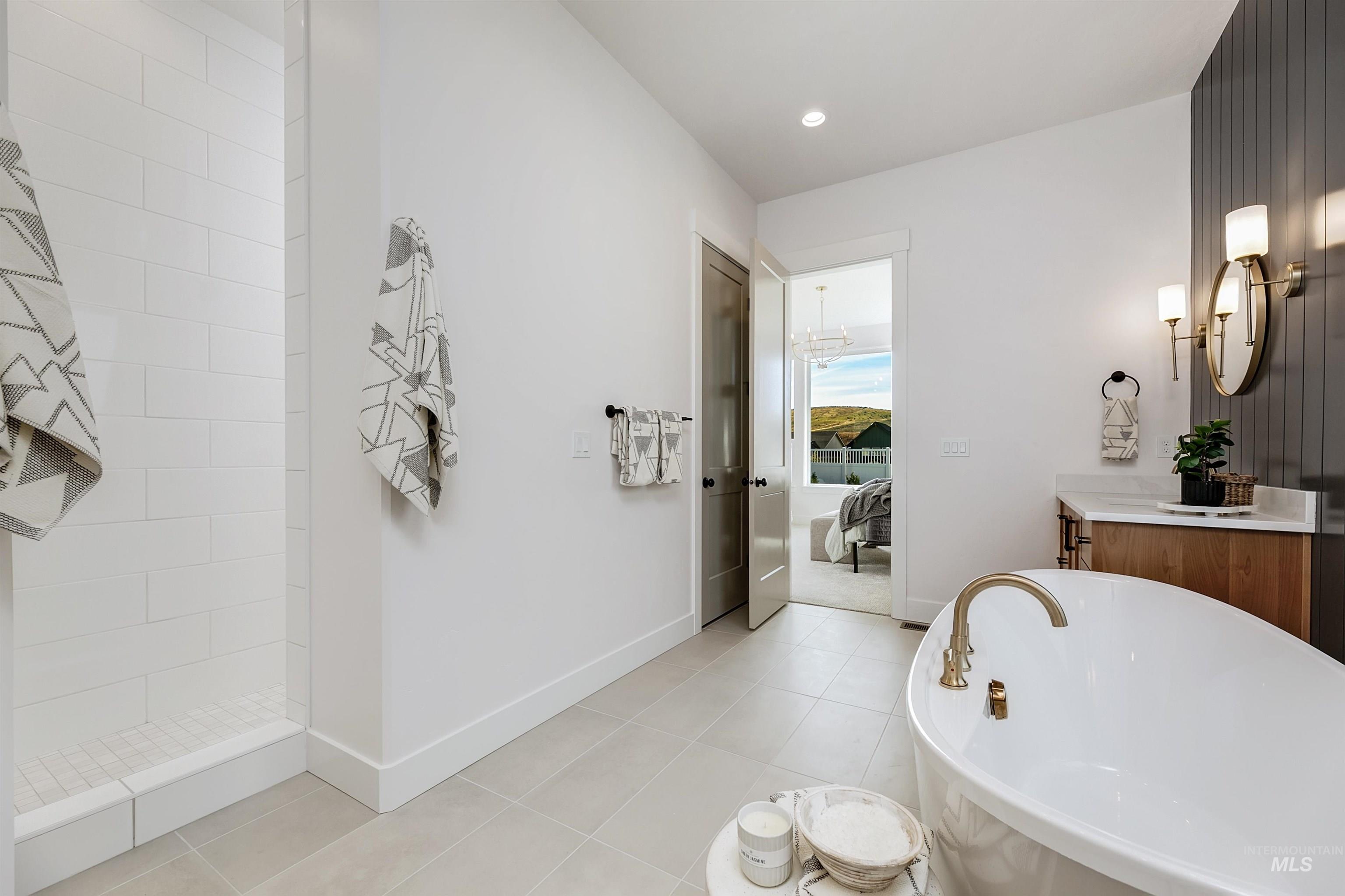 Ensuite bathroom with vanity, a freestanding tub, light tile patterned floors, and recessed lighting