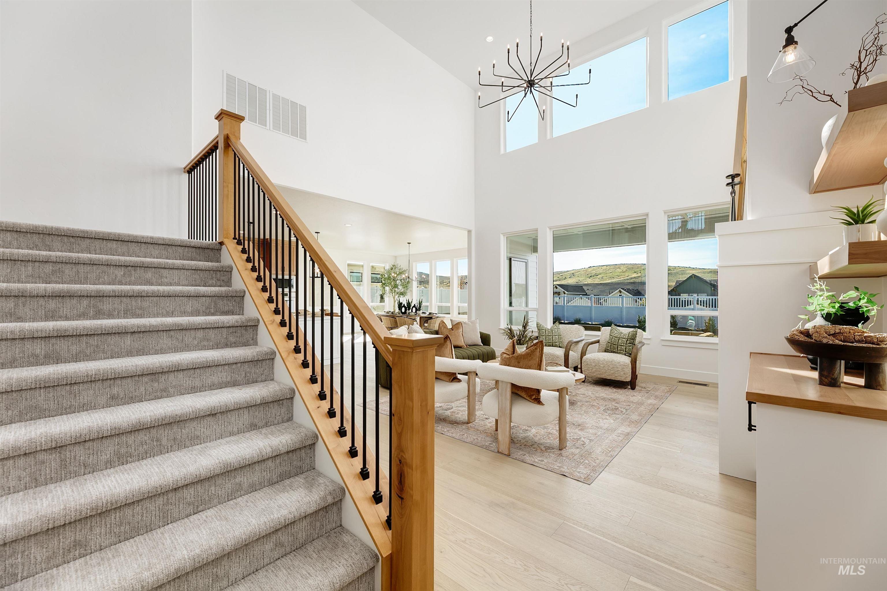 Stairs with a chandelier, wood finished floors, and a towering ceiling