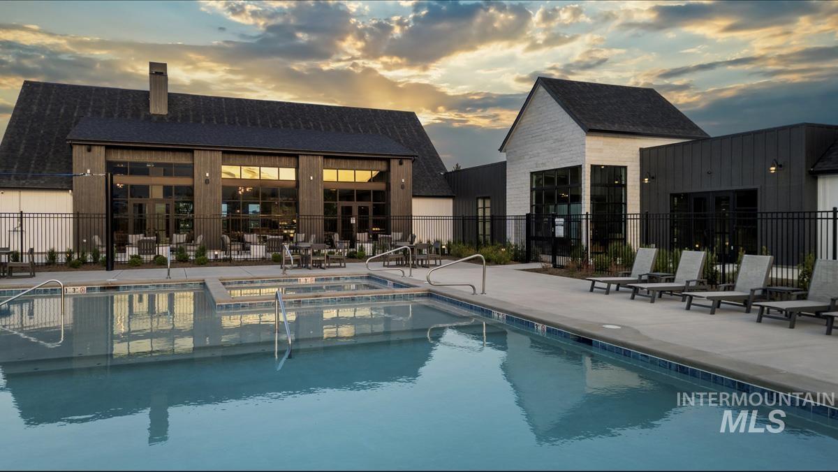 Pool at dusk with a patio area and a pool with connected hot tub