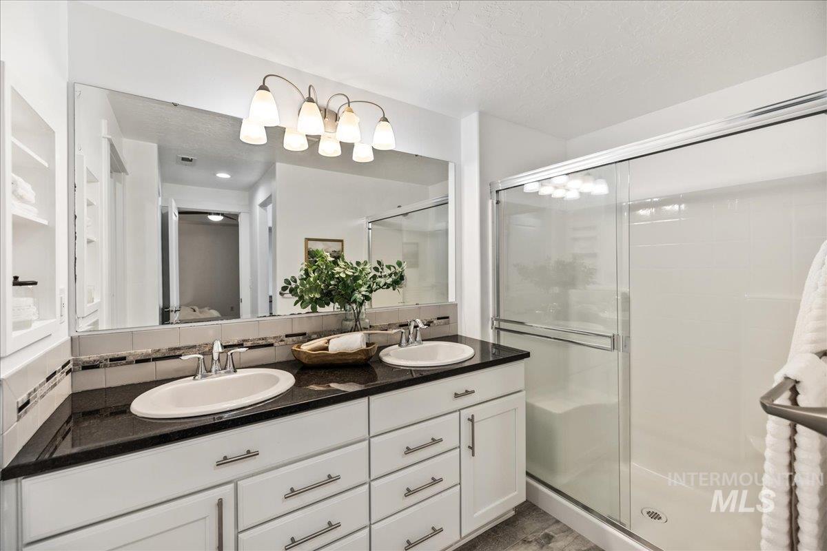 Ensuite bathroom with double vanity, a textured ceiling, and a stall shower
