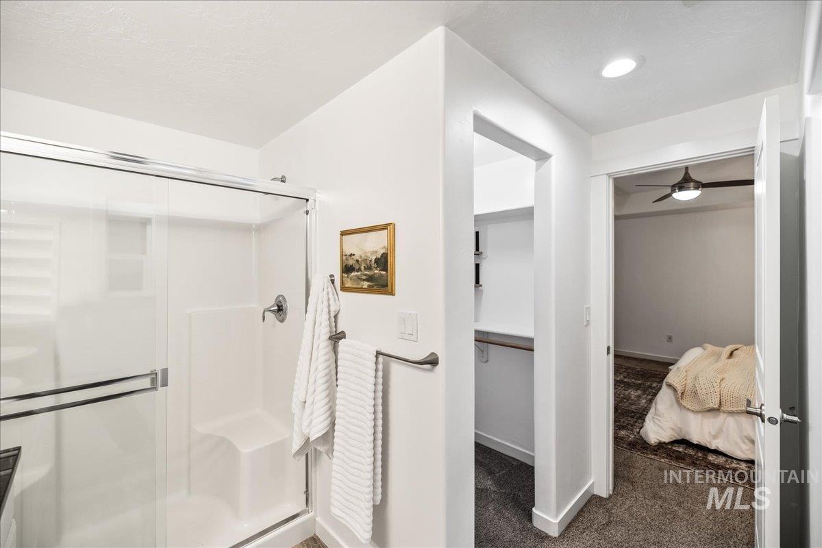 Ensuite bathroom with a shower stall, carpet flooring, and ceiling fan