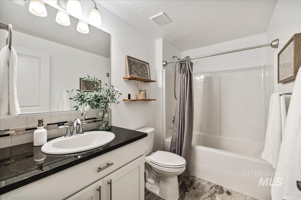 Full bathroom featuring shower / bath combination with curtain, vanity, and backsplash