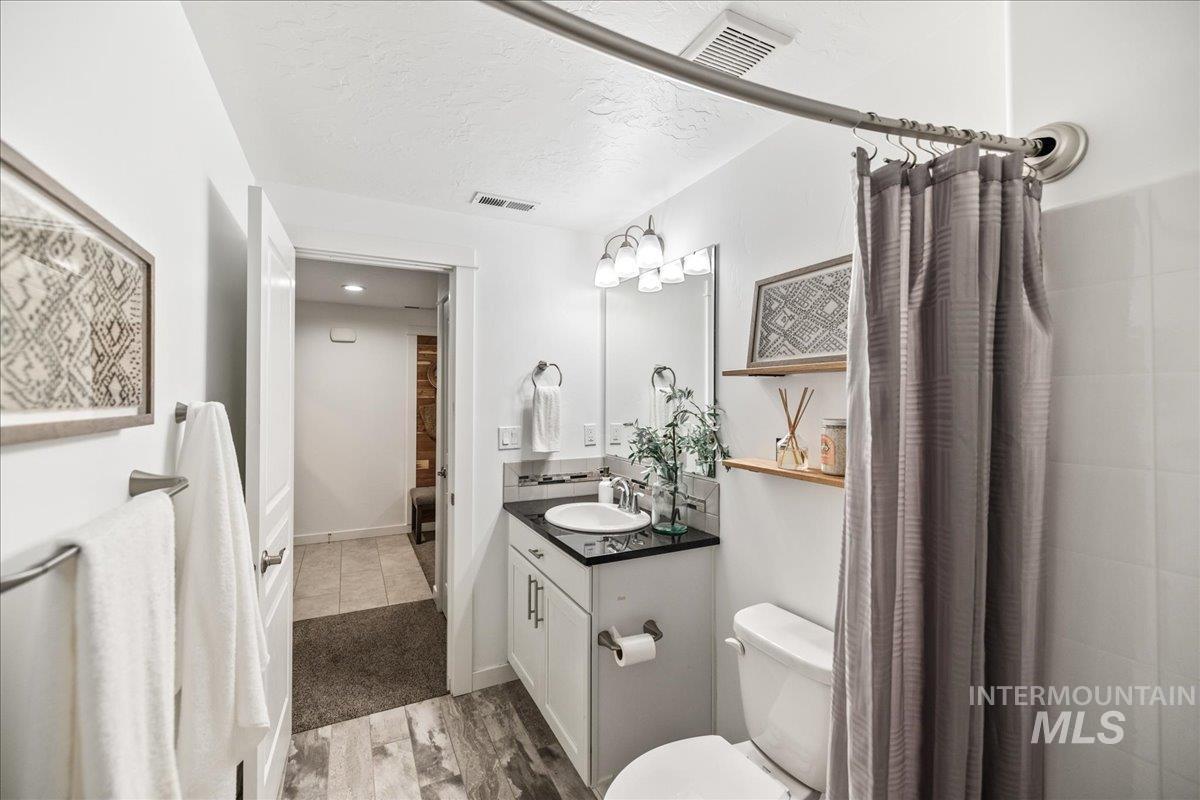 Bathroom featuring light wood-type flooring, vanity, a textured ceiling, and a shower with curtain
