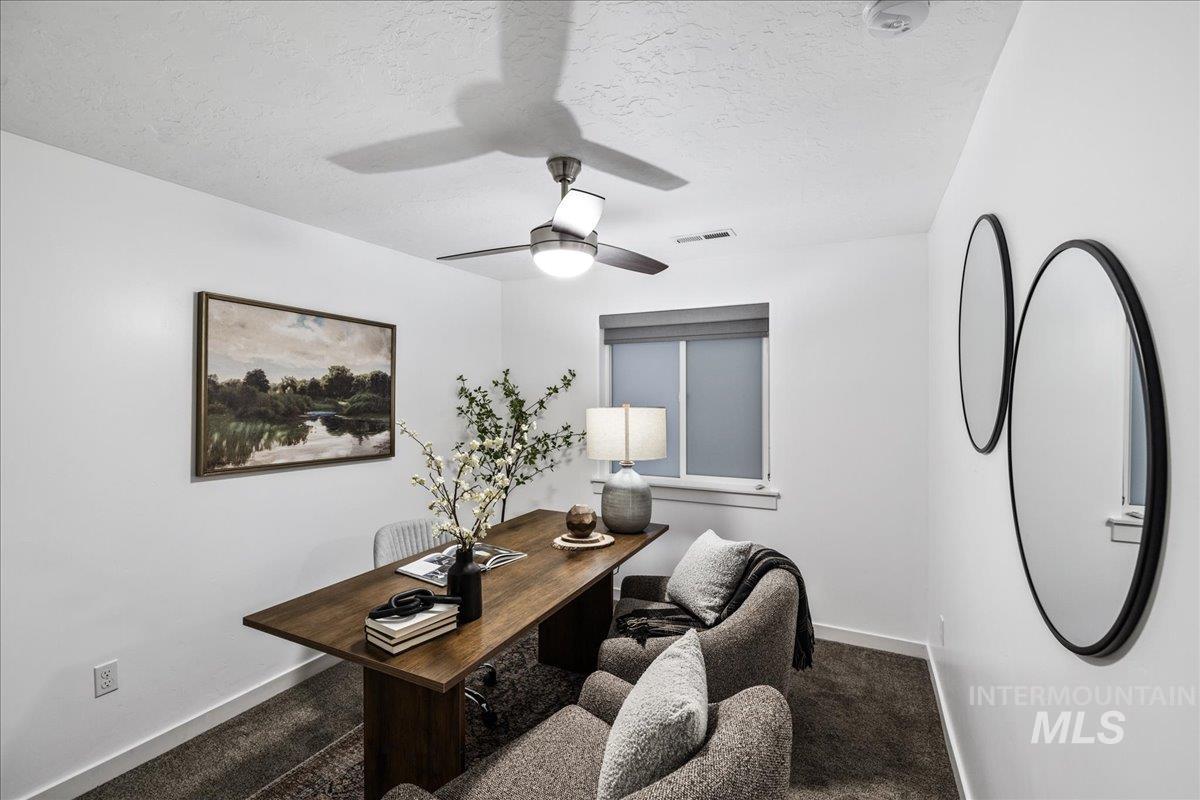 Home office featuring a textured ceiling, carpet, and a ceiling fan