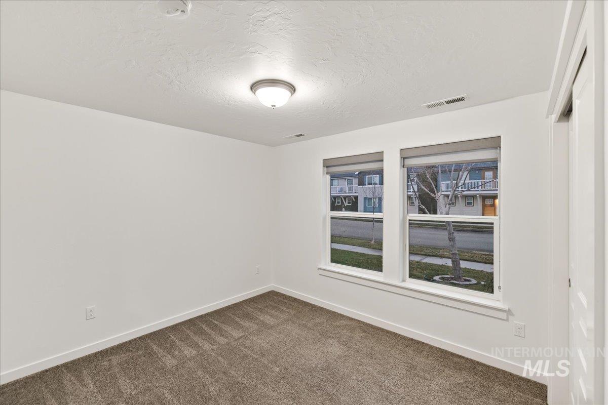 Spare room featuring a textured ceiling and dark carpet