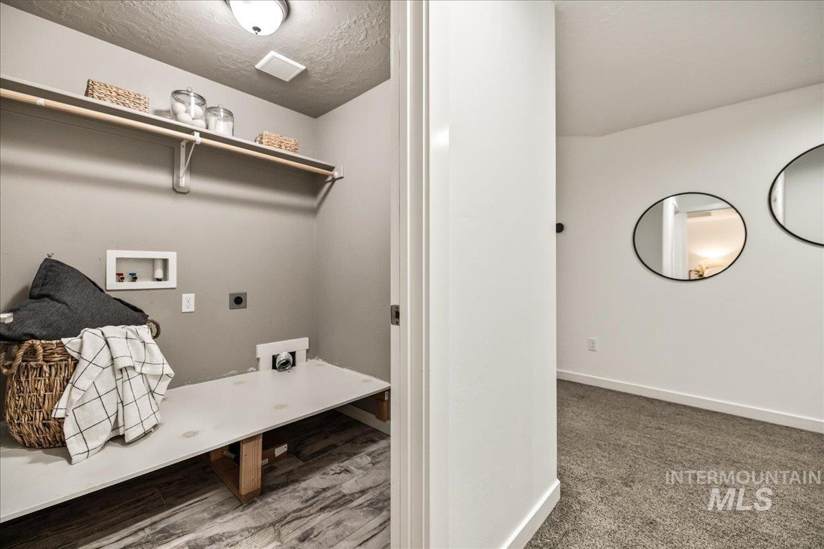 Laundry room featuring washer hookup, electric dryer hookup, a textured ceiling, and wood finished floors