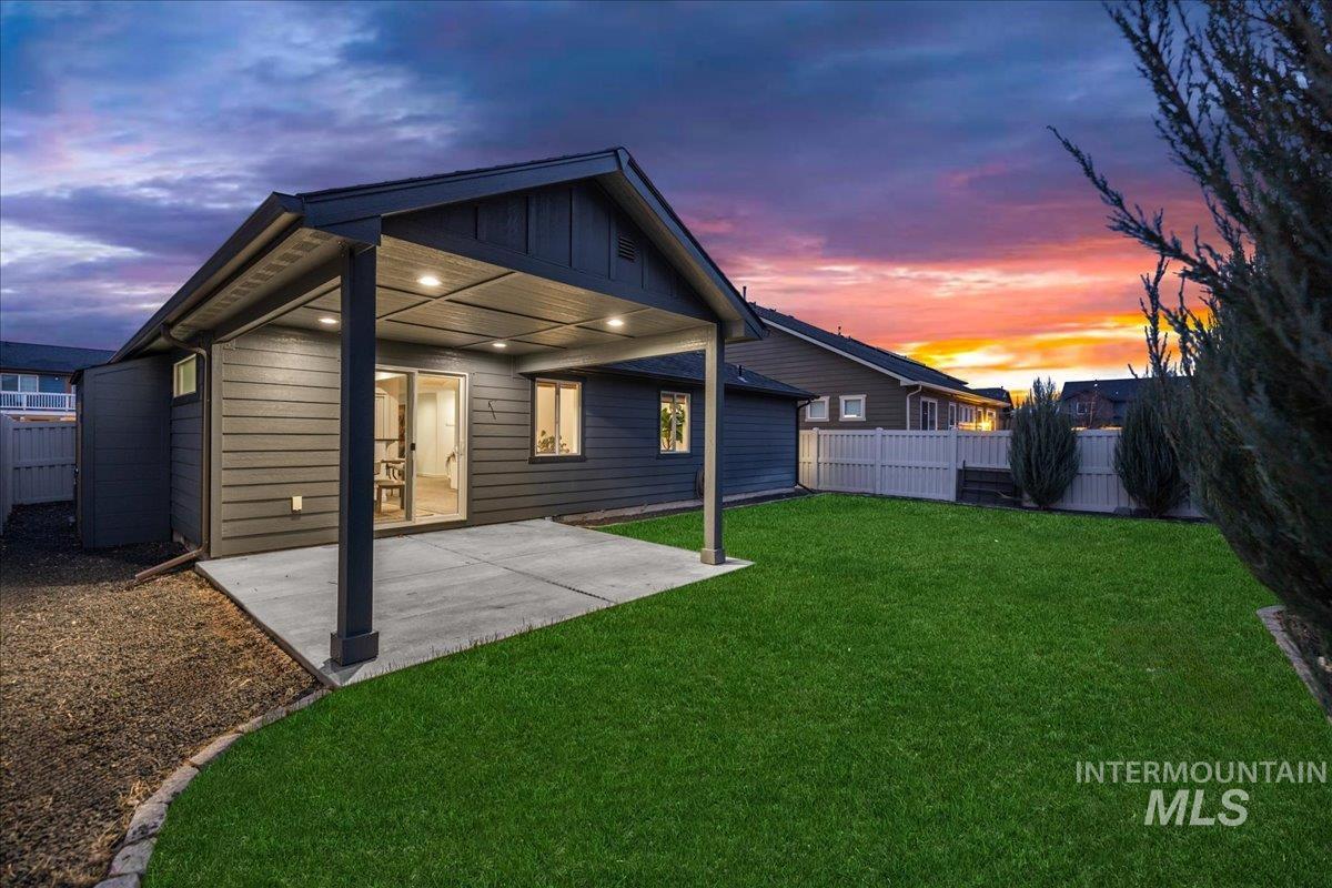 Back of property at dusk featuring a patio area, a fenced backyard, and board and batten siding