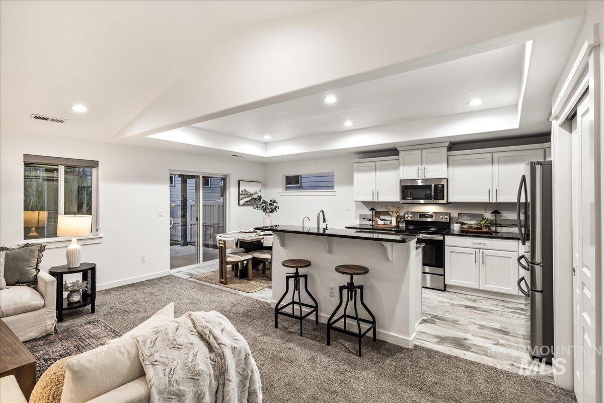 Kitchen with open floor plan, a kitchen bar, light carpet, recessed lighting, and lofted ceiling