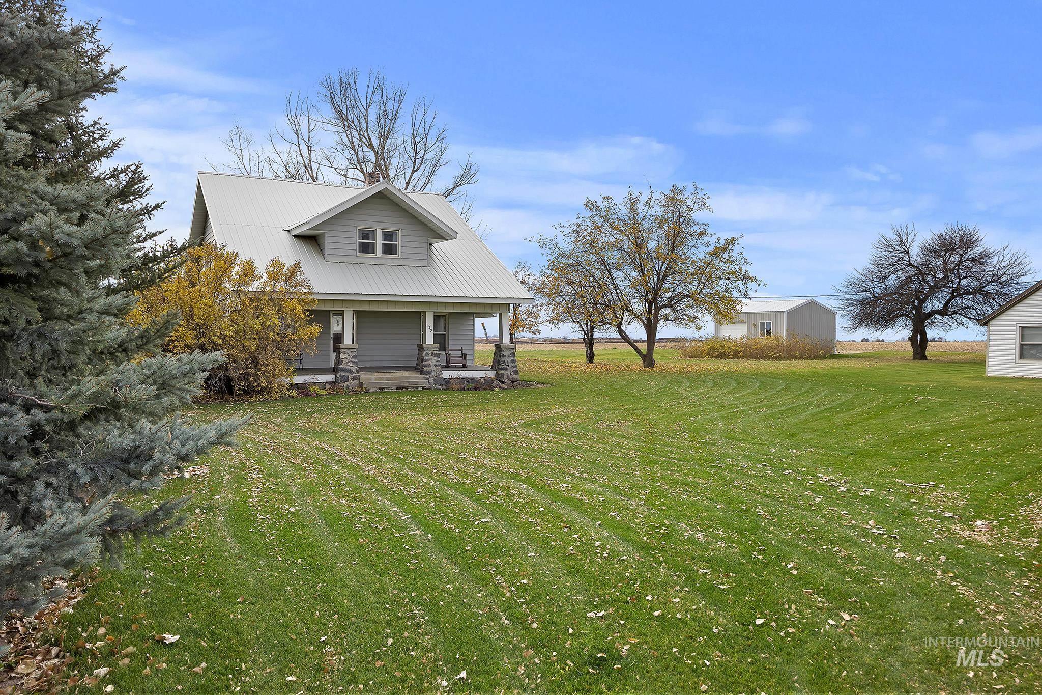 Rear view of house featuring a porch, a yard, and a metal roof