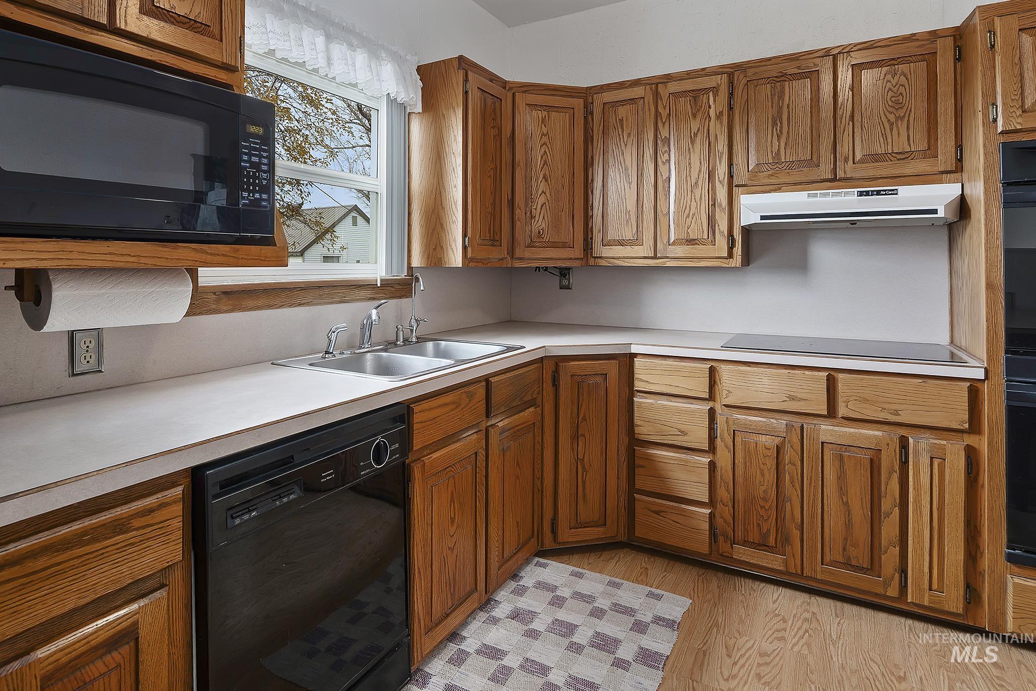 Kitchen featuring black appliances, brown cabinets, and light countertops