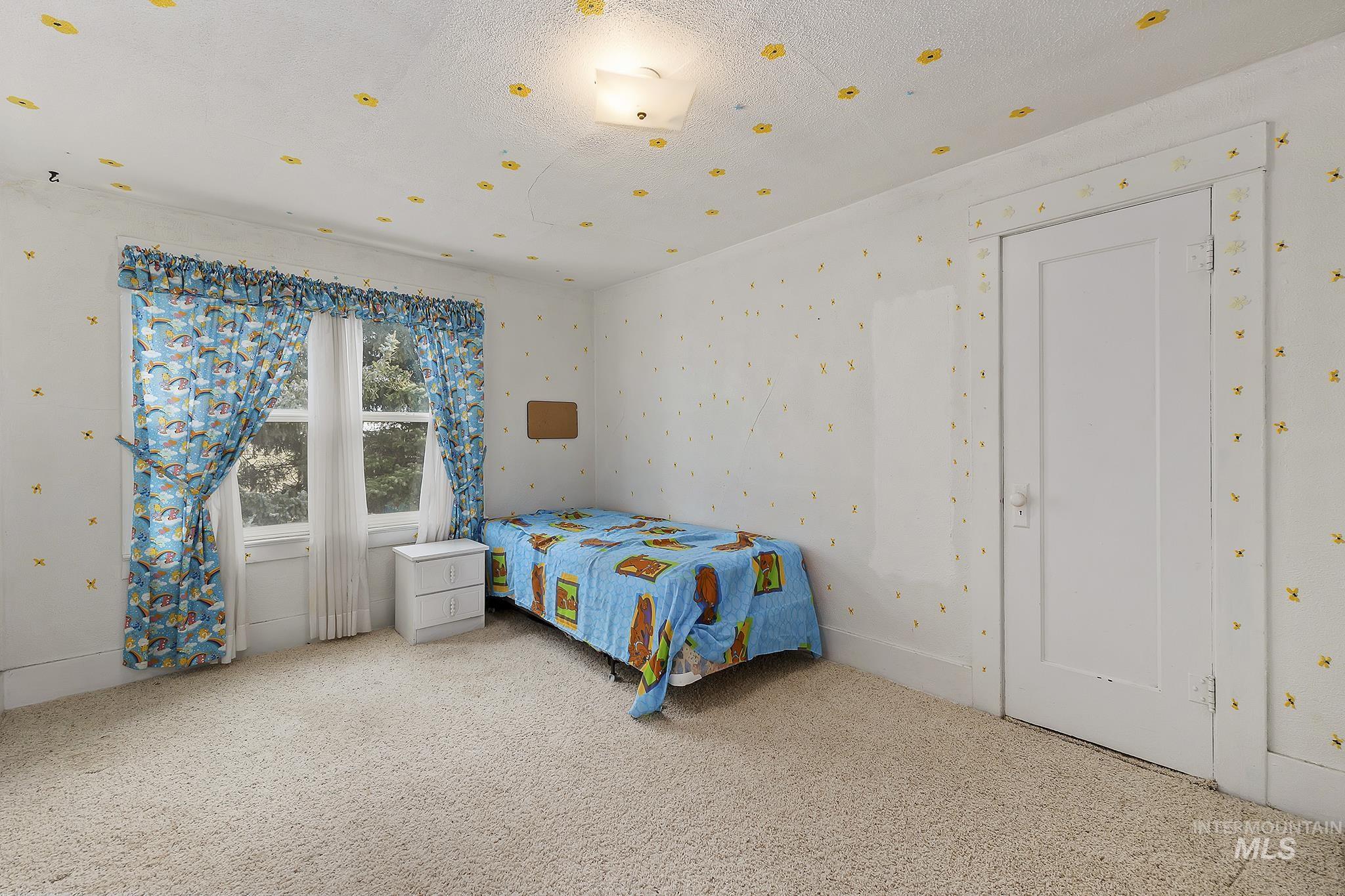 Bedroom featuring carpet floors, wallpapered walls, and a textured ceiling