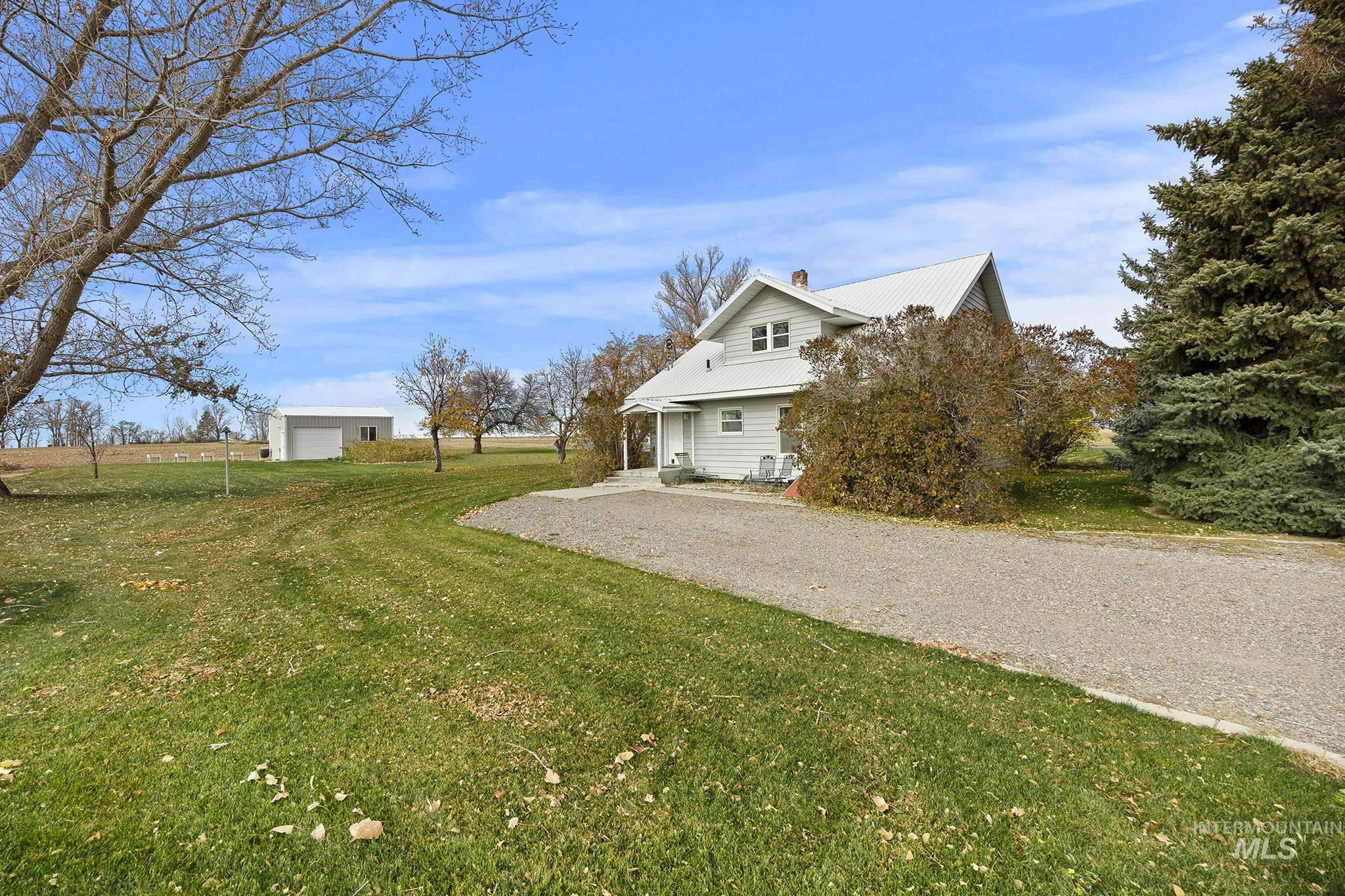 View of side of property with a lawn, a metal roof, a chimney, an outdoor structure, and driveway