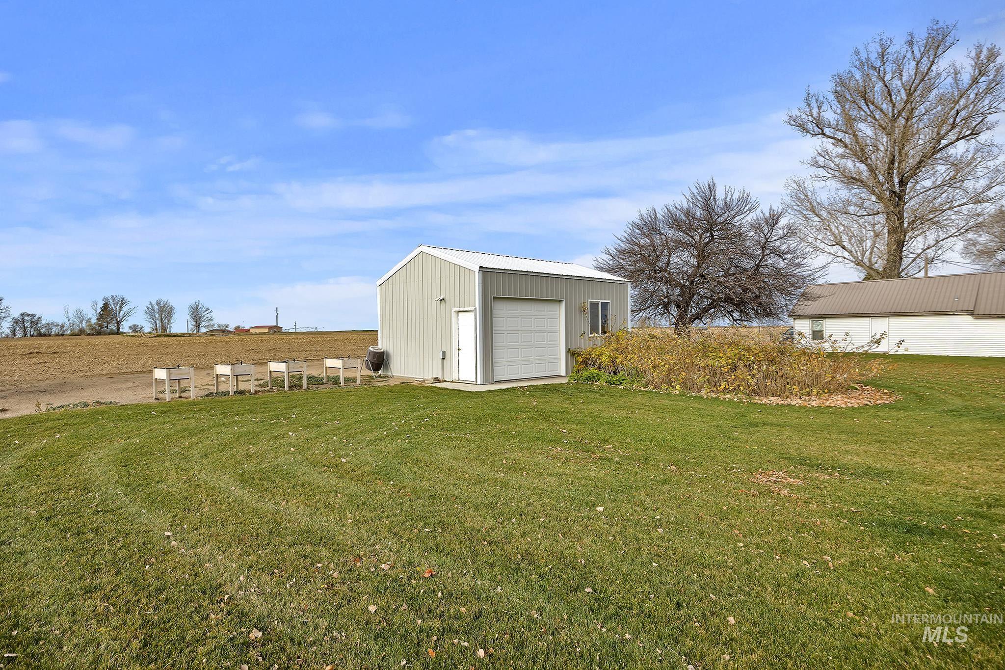 View of green lawn with an outdoor structure and a garage