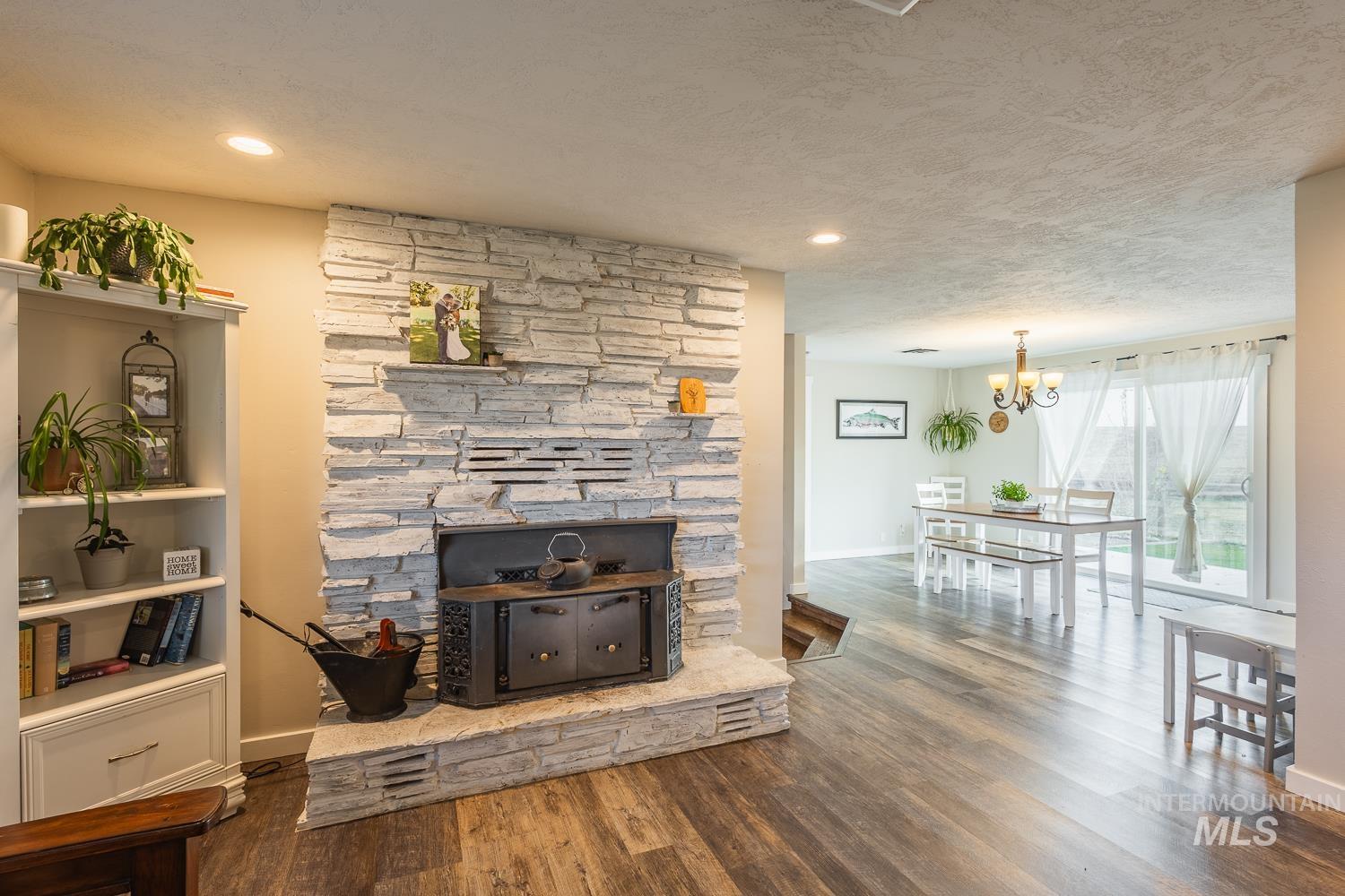 Living room with wood finished floors, a chandelier, a textured ceiling, and recessed lighting