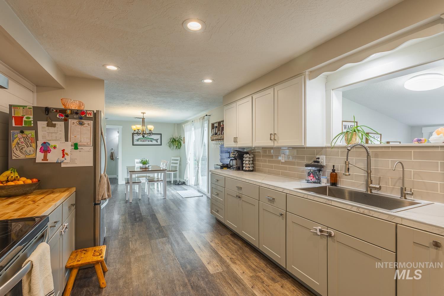 Kitchen with light countertops, a textured ceiling, dark wood-style flooring, tasteful backsplash, and recessed lighting