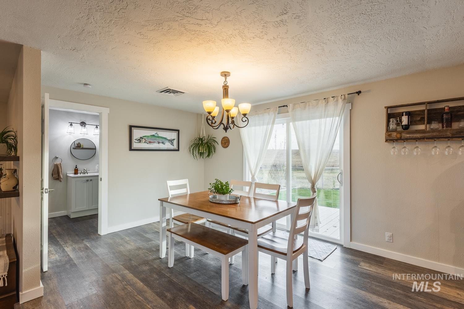 Dining area featuring a textured ceiling, dark wood-style floors, and a chandelier