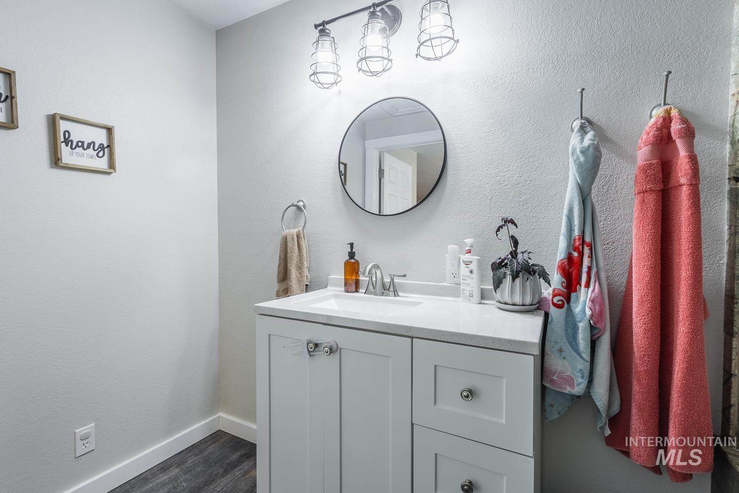 Bathroom featuring a textured wall, vanity, and dark wood-style flooring