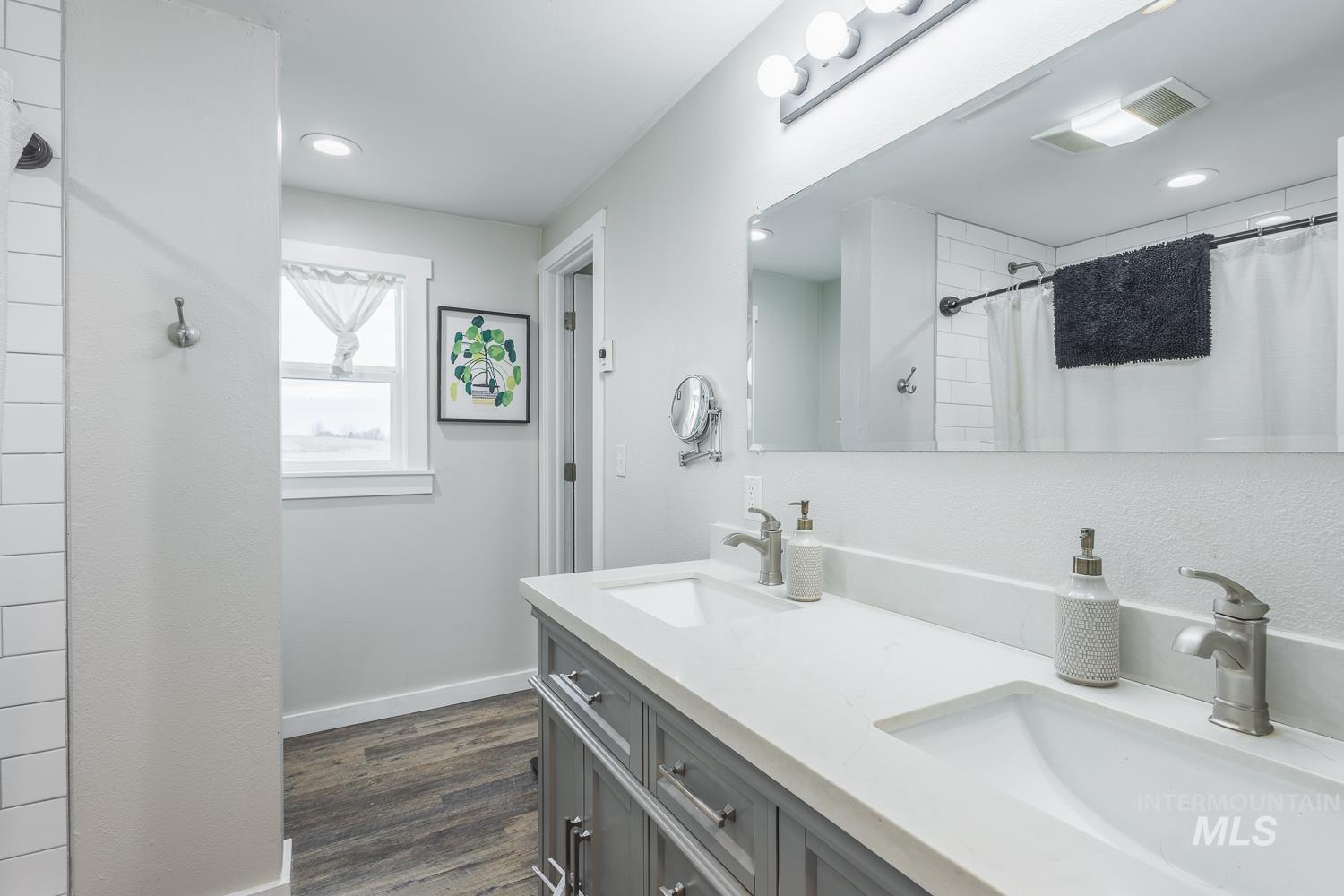 Bathroom with double vanity, a shower with curtain, dark wood-type flooring, and recessed lighting