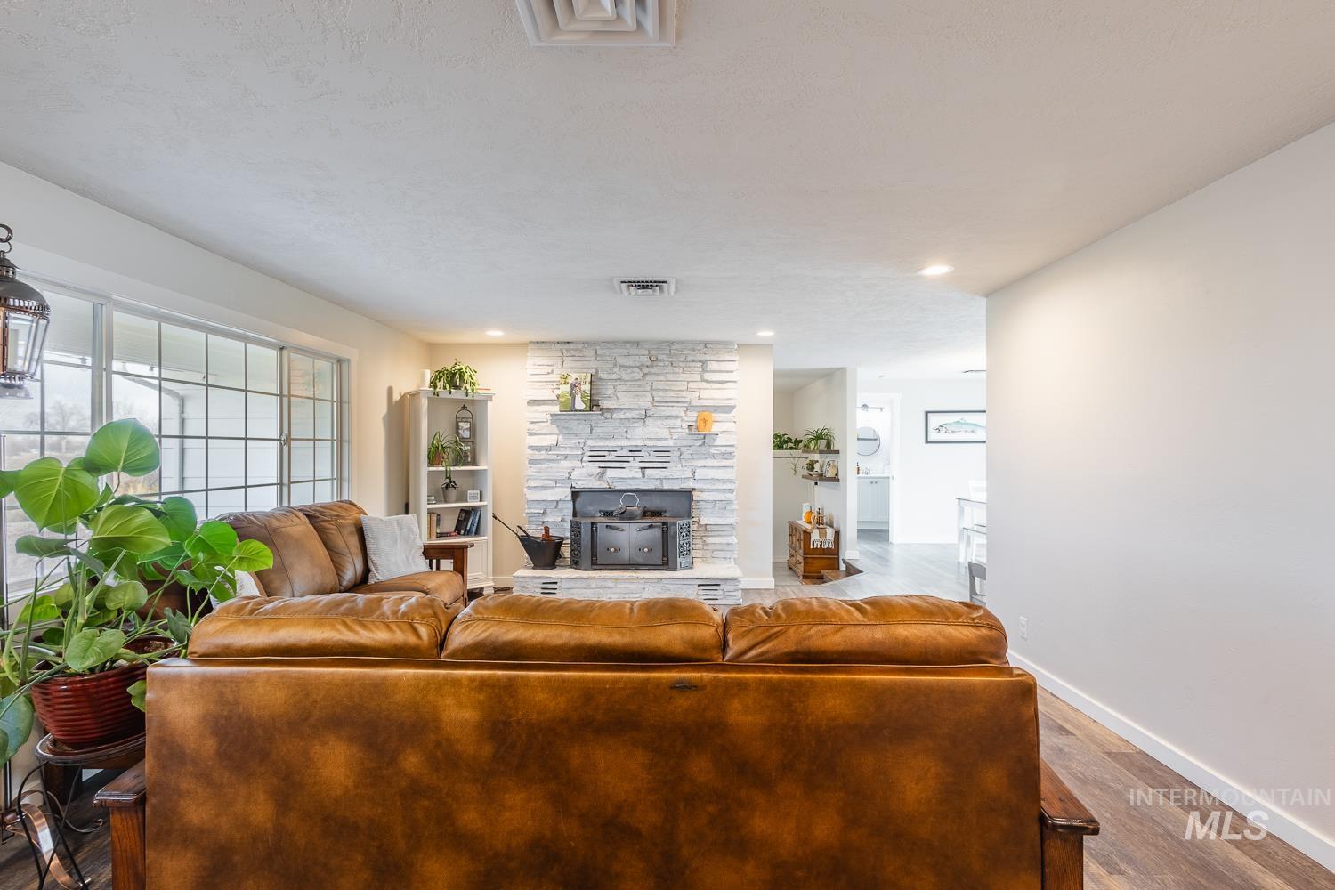 Living area featuring wood finished floors, recessed lighting, a stone fireplace, and a textured ceiling
