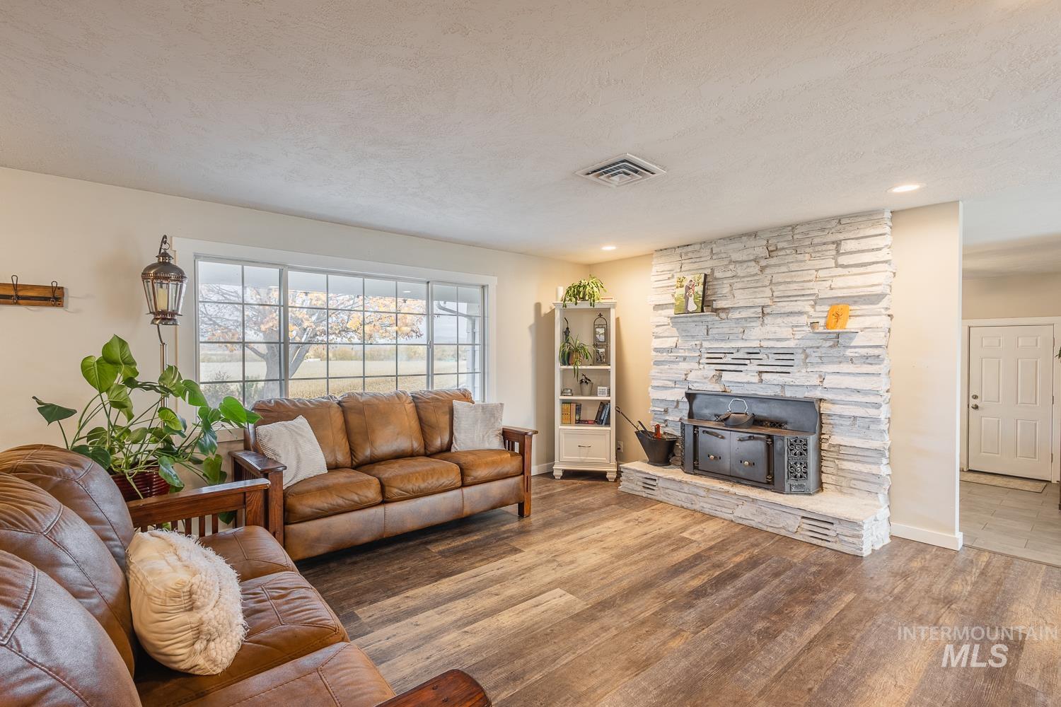 Living area with wood finished floors, a textured ceiling, and a fireplace