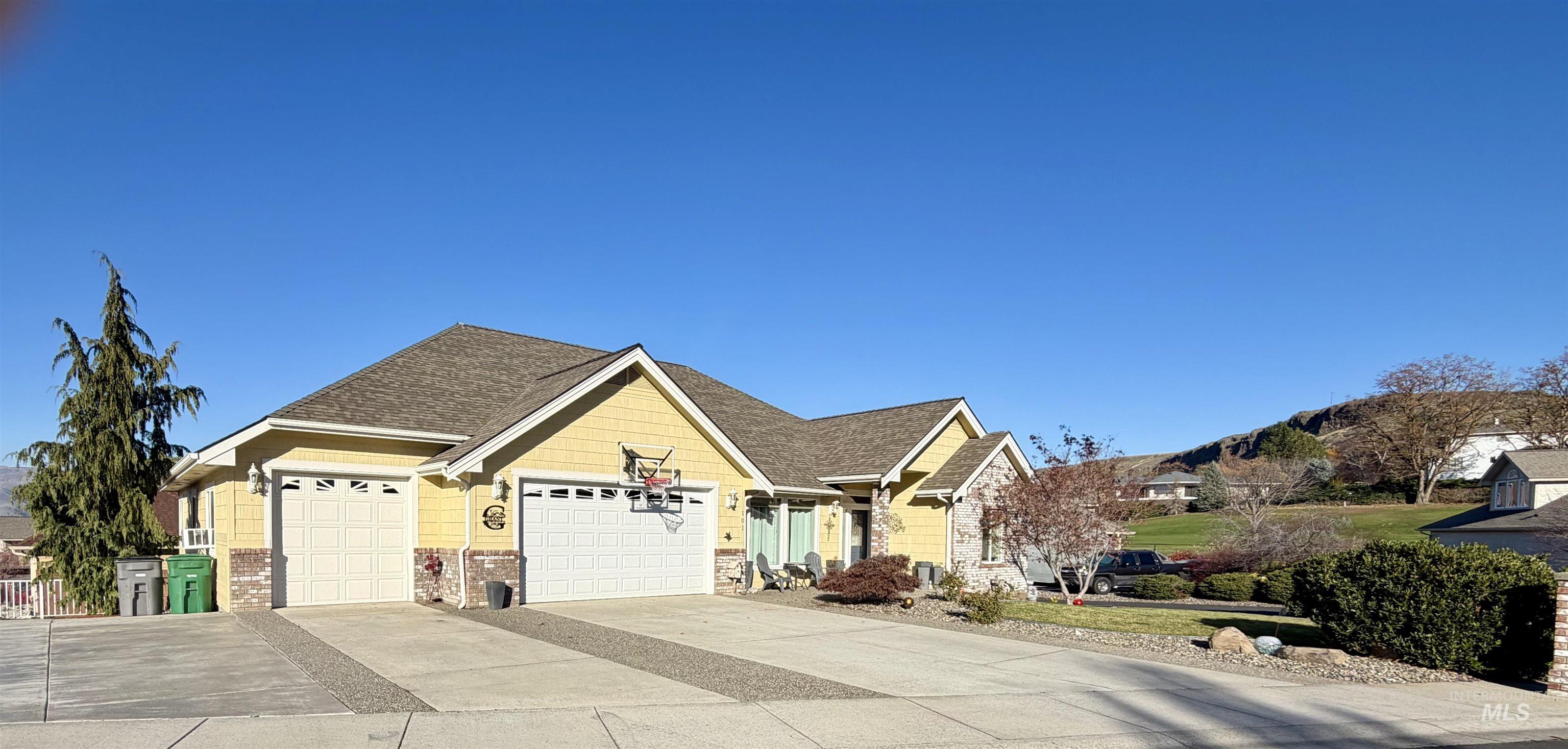 View of front facade featuring concrete driveway, a garage, and a shingled roof