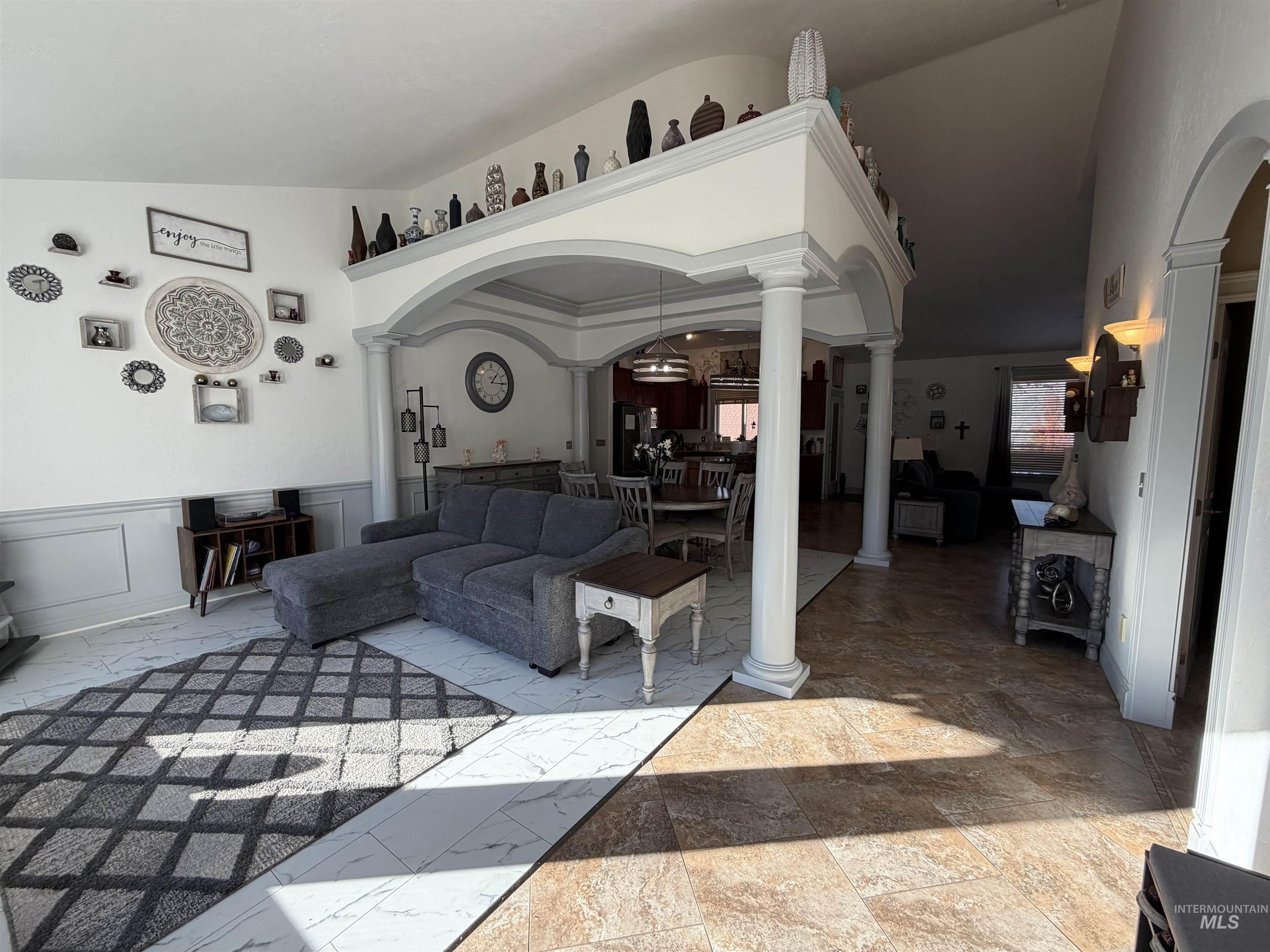 Living area featuring ornate columns, arched walkways, and lofted ceiling