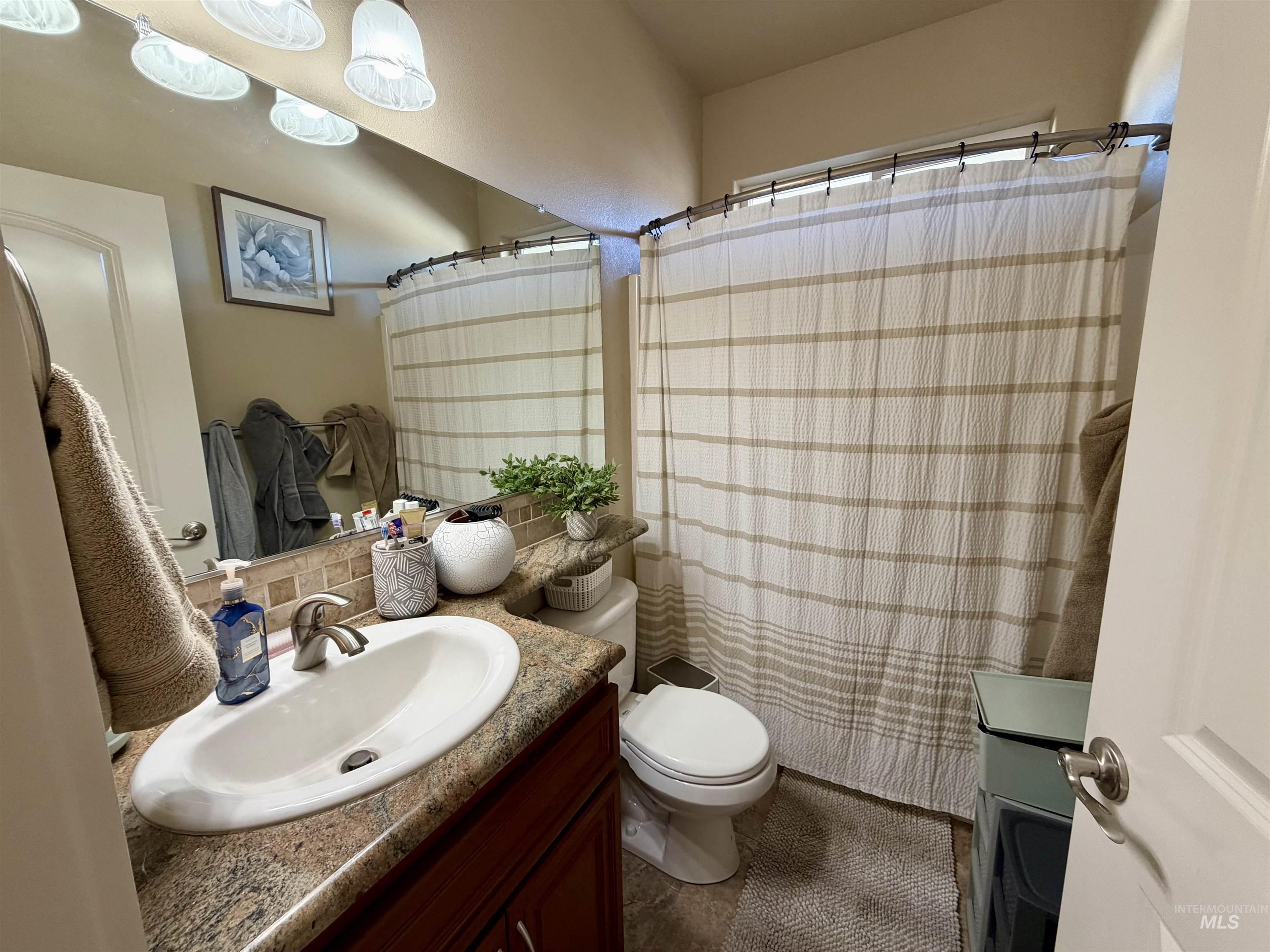 Full bath featuring vanity, a shower with shower curtain, and backsplash
