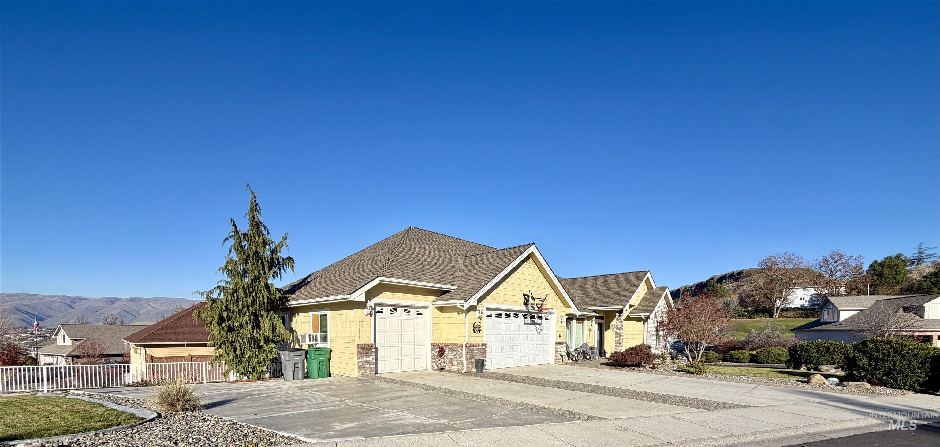 Craftsman inspired home featuring concrete driveway, an attached garage, a residential view, a mountain view, and a shingled roof